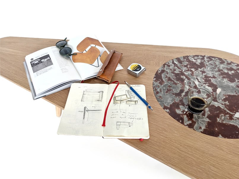 Table sur mesure en chêne avec incrustation d'un marbre. détail du dessus avec livres et café.